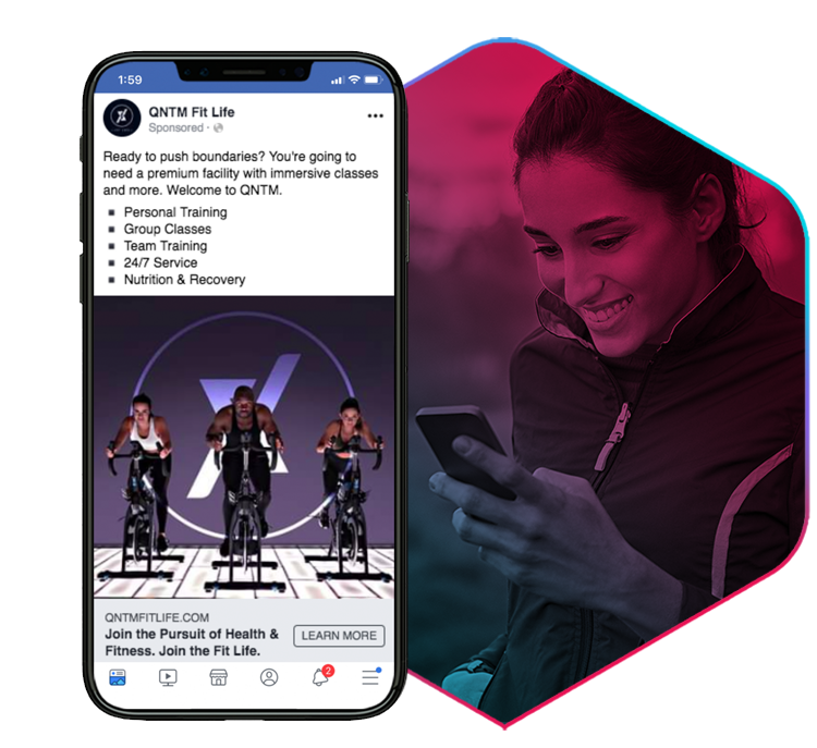 an iPhone X with QNTM fitness facebook ad and a girl looking at her phone in the background